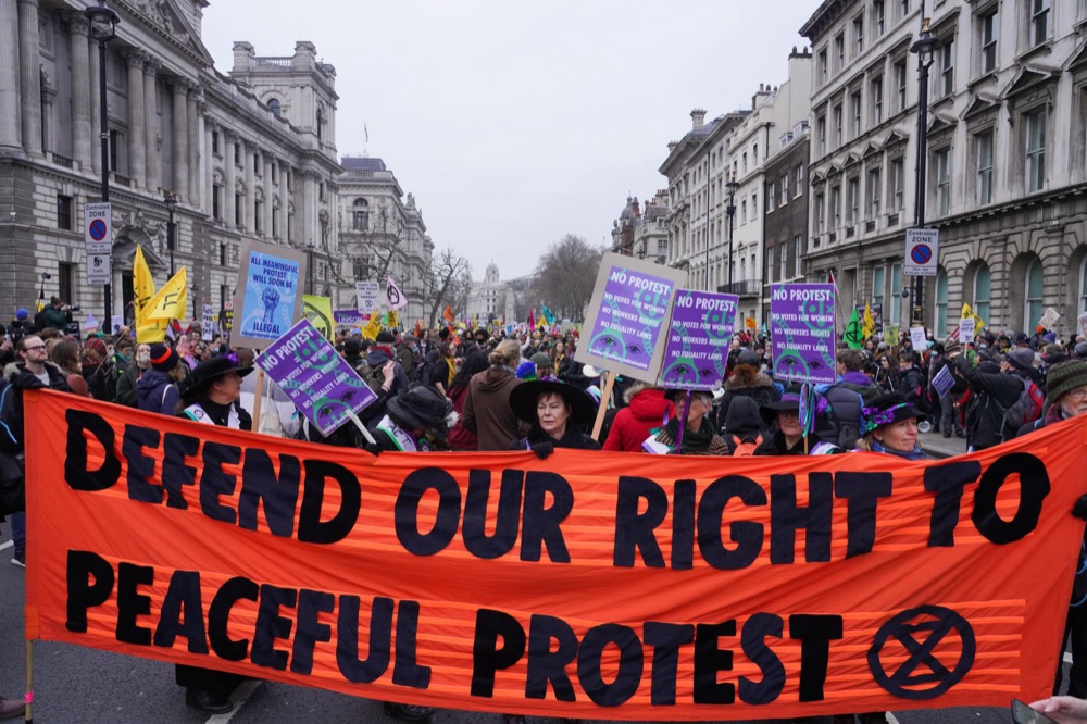 Protesters holding a banner reading Defend our right to peaceful protest